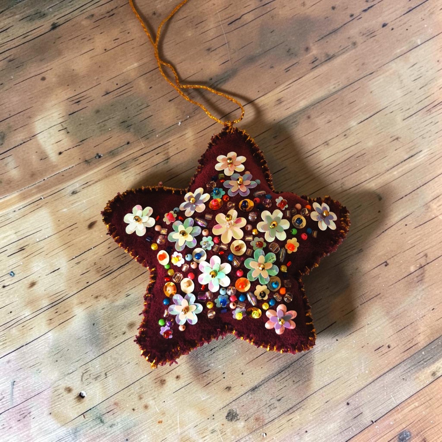 Étoile de Noël Thalie's Factory en velours bordeaux, ornée de fleurs et perles multicolores cousues à la main.